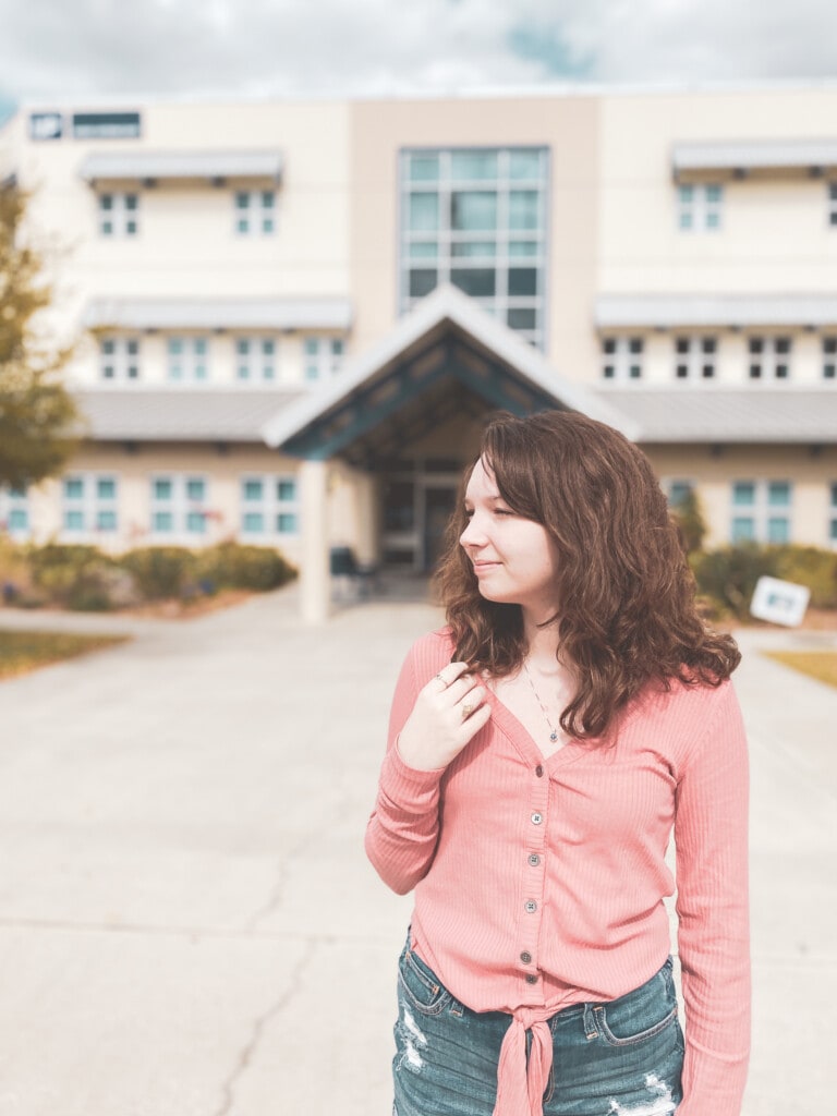 girl standing in front of building thinking about college