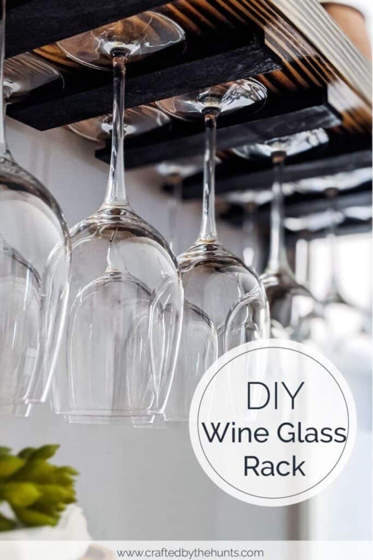 A wine glass rack made of dark wood with large win glasses hooked upside down from it