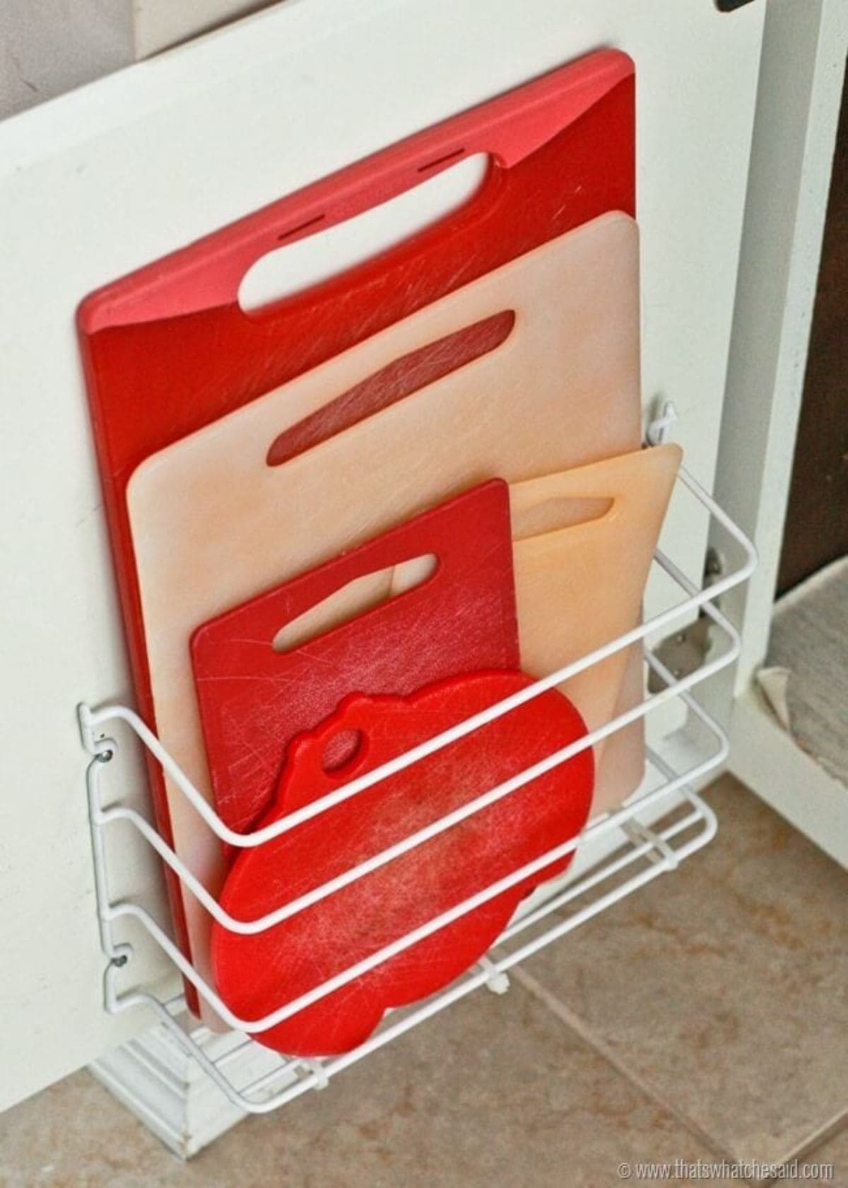 Inside the door of a cupboard a wire magazine rack has been fitted. Inside are red and white chopping boards